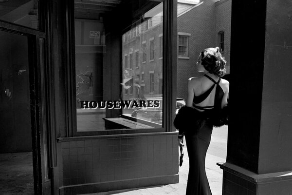 Black and white photo of a girl with a back near the showcase