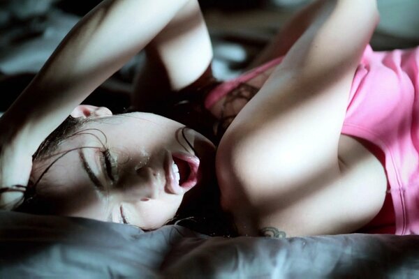 Brunette on the bed in a pink tank top