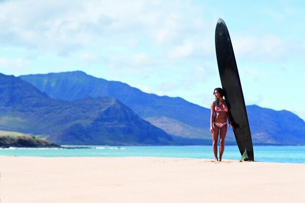 Girl with a surfboard on the beach