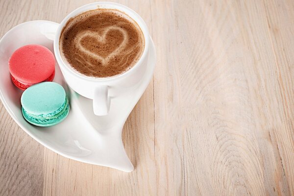 Eine Tasse Kaffee mit Herz auf Schaum und zwei Kuchen