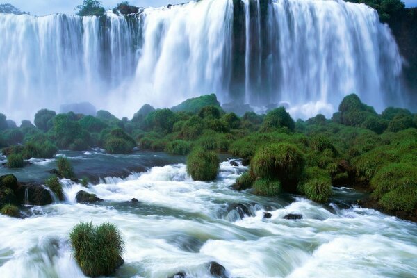 A stormy waterfall, turning into a river, among greenery