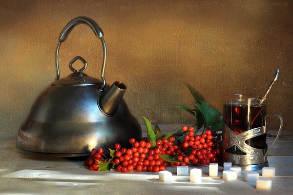 Ein Wasserkocher und eine Tasse Tee auf dem Tisch. Rote Beeren mit Tee