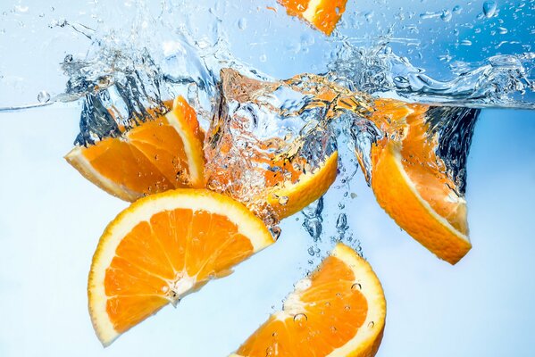 Rodajas de naranja caen en el agua