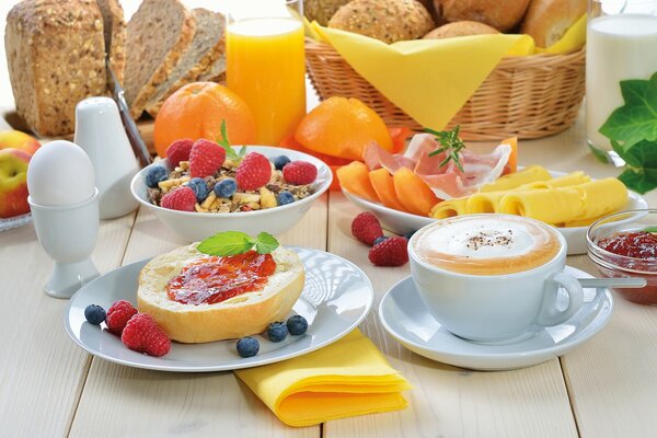 Breakfast consisting of a soft-boiled egg, toast with jam, fruit, cheese and a cup of cappuccino