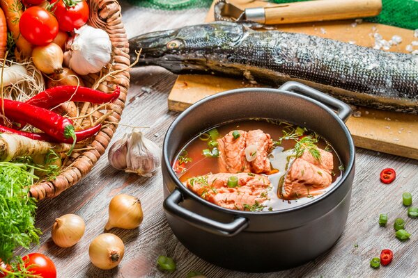 Oreja en una sartén sobre el fondo de un pescado en una tabla de cortar y una canasta de verduras