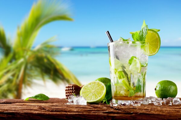 A glass of mojito on the background of the ocean and palm trees