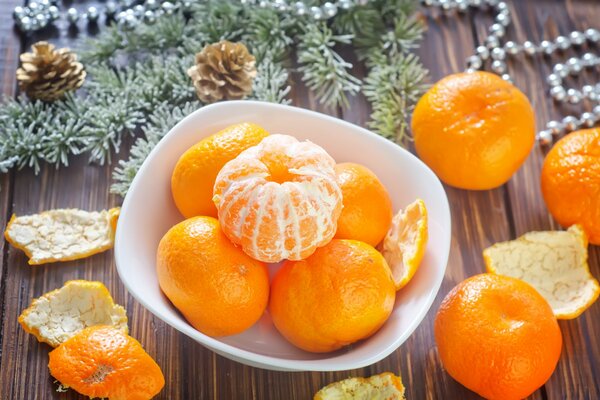 Winter holiday. Orange citrus fruits on a plate. Surrounded by peel and spruce