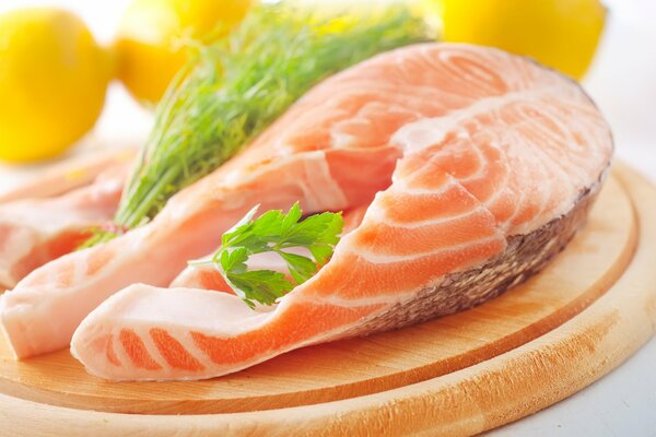 Filete de salmón rojo en una tabla de madera decorada con vegetación