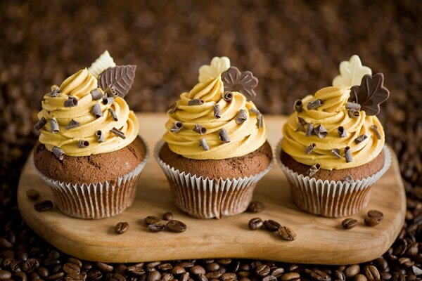 Drei Muffins auf einer Tafel mit Sahne und Schokolade