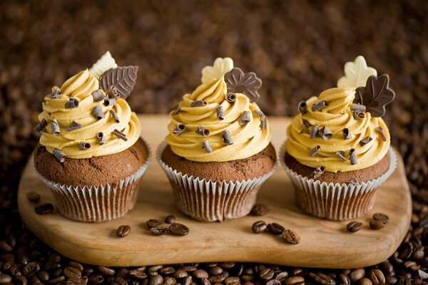 Trois cupcakes sur un tableau noir avec crème et chocolat