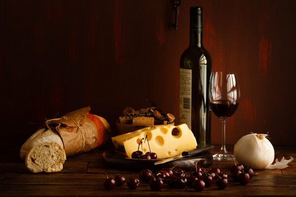 A bottle of red wine with cheese and cherries