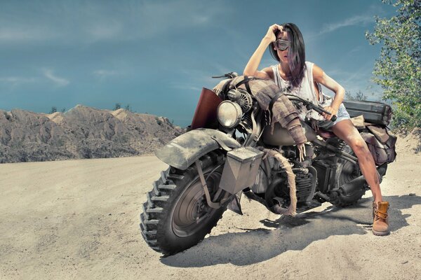 Schönes Mädchen auf einem Motorrad in der Wüste