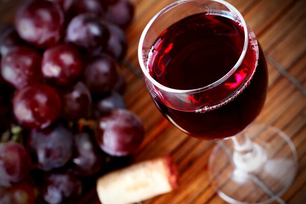 Ein Glas Wein mit Traubenwein und Trauben, die auf dem Tisch liegen