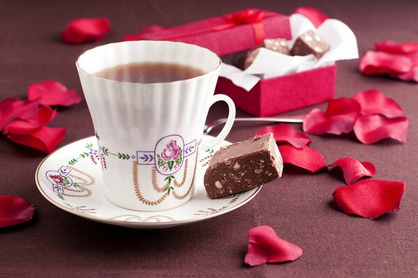 Taza de té en la mesa con pétalos de rosa