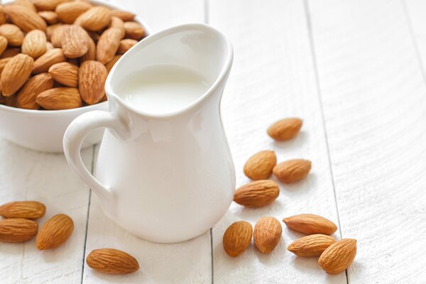 Milk in a jug next to almonds