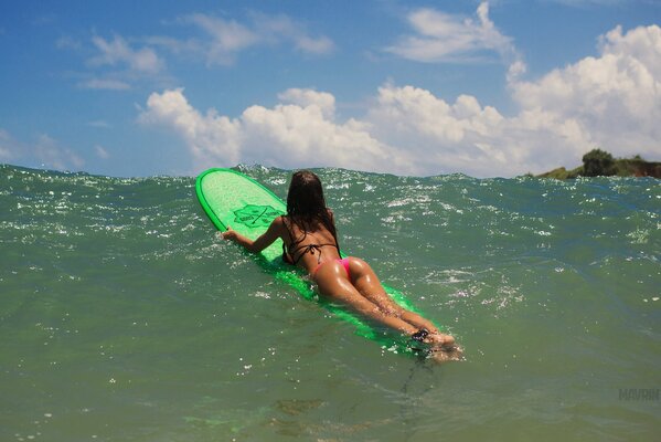 Dziewczyna na surfingu leży w kostiumie kąpielowym