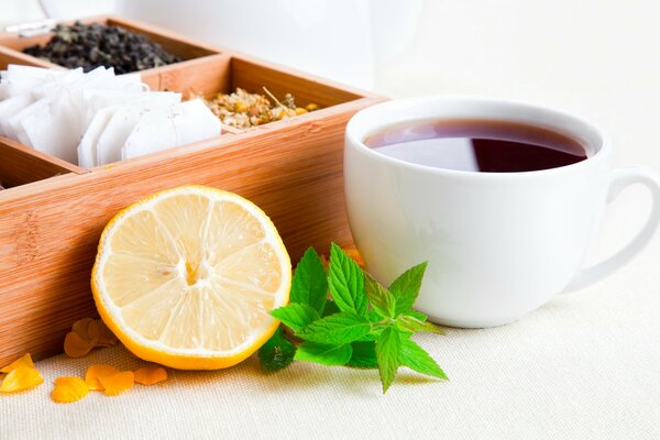 Tea set on the table . Lemon , tea , mint and short with spices and tea