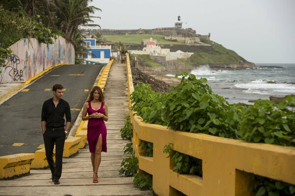 Justin Timberlake and Gemma Arterton walk along the fence on the seashore