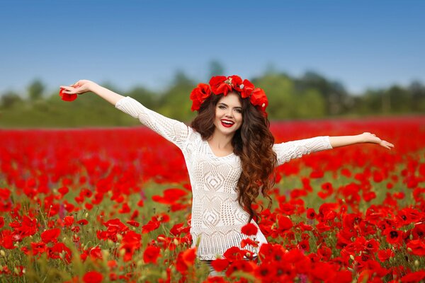 A brown-haired woman smiles against the background of a field of poppies