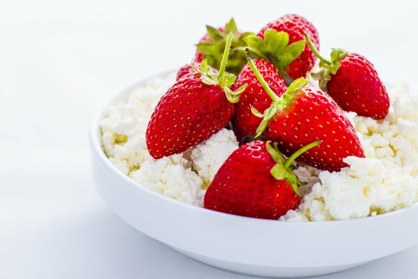 Strawberry with cottage cheese in a plate on a white background