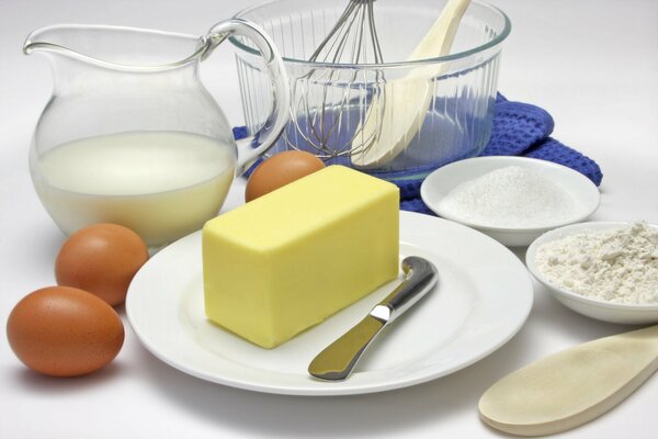 A set of products on the table . Butter, milk, eggs, flour and cutlery