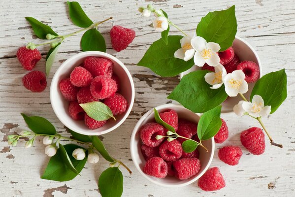 Tassen mit Himbeerbeeren und Jasminblüten