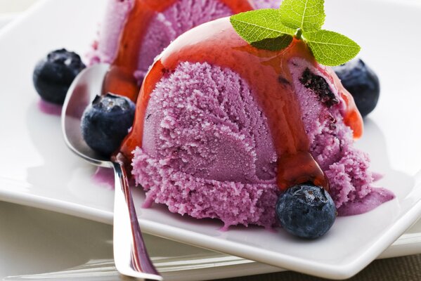 Ice cream poured with syrup with mint leaves and blueberries