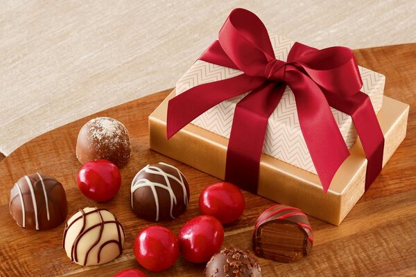Chocolates and a gift box with a ribbon on the table