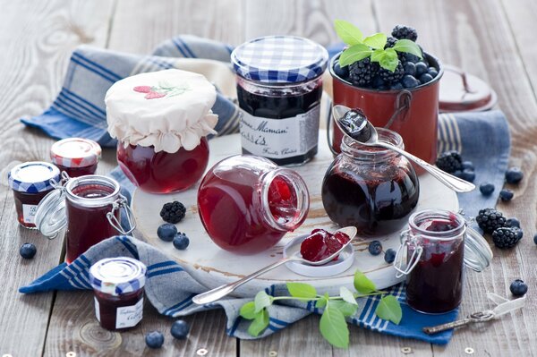 Marmeladengläser neben Blaubeeren und Brombeeren