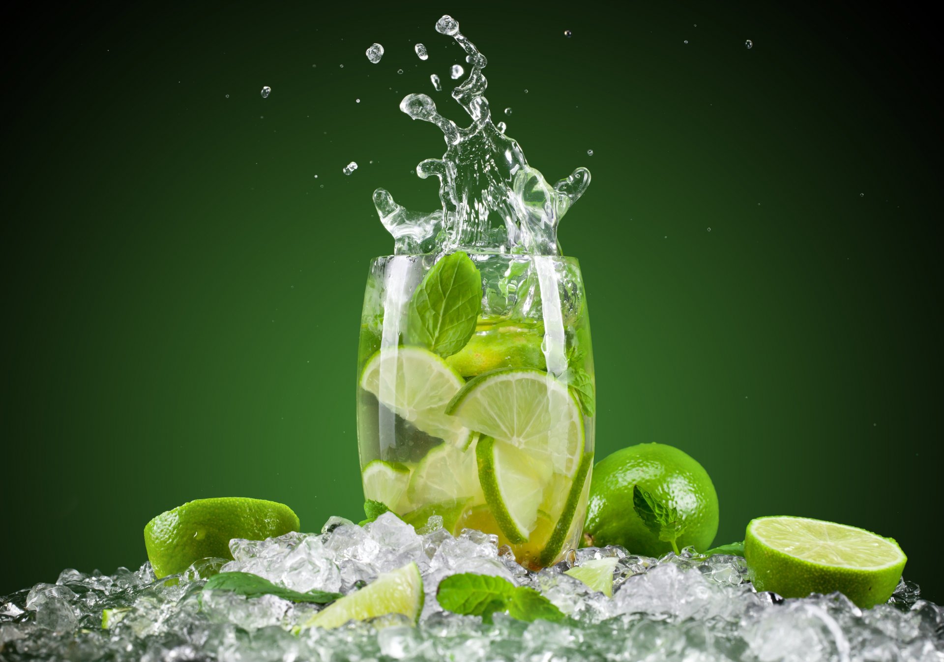 mojito cocktail glass next lima citrus fruits spray background green