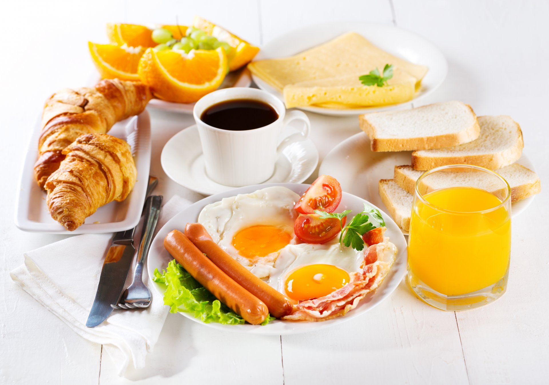 petit déjeuner œufs brouillés bacon saucisses tomates toasts pain fromage jus oranges bagels croissants café