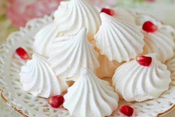 White meringue on a plate with pomegranate seeds