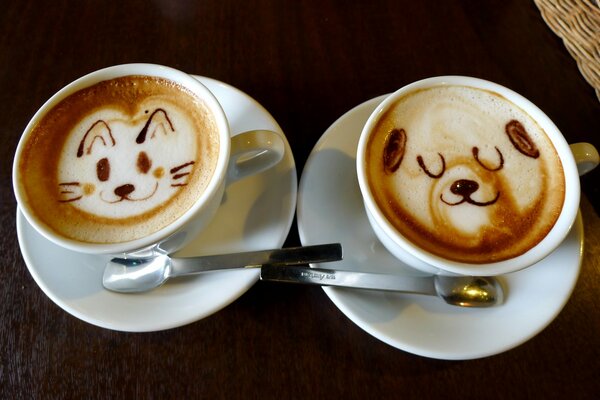 Dwie filiżanki cappuccino i wzory na piance: kot i pies zadowoleni