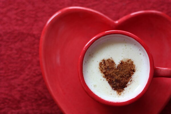 Taza de café con leche adornada con un corazón de cacao