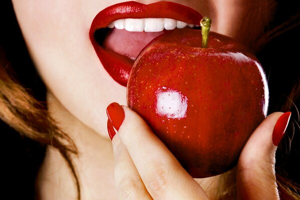 La boca de la niña muerde la manzana roja