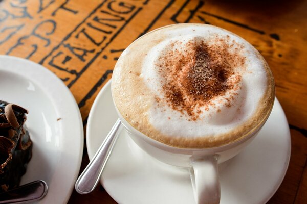 Cappuccino with foam and cake on a plate