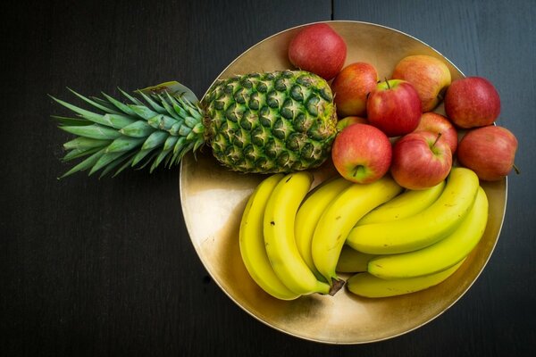 Manzana plátano y piña se encuentran en un plato