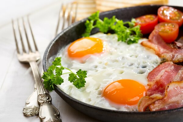 Delicious breakfast of two eggs and bacon with tomatoes