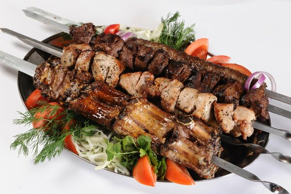 Barbecue on a platter with vegetables and herbs