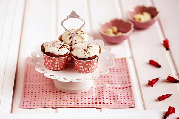 Rosa Muffins mit Blütenblättern auf einer Serviette