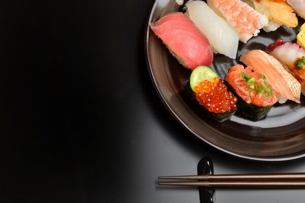 Sushi with chopsticks on a black background