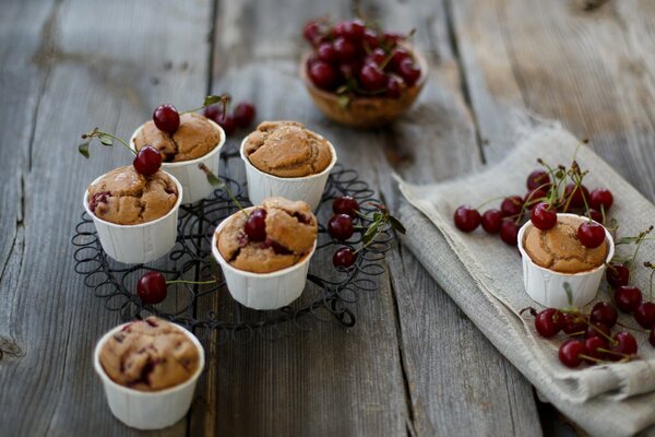 Kleine Muffins in Tassen mit Kirschen