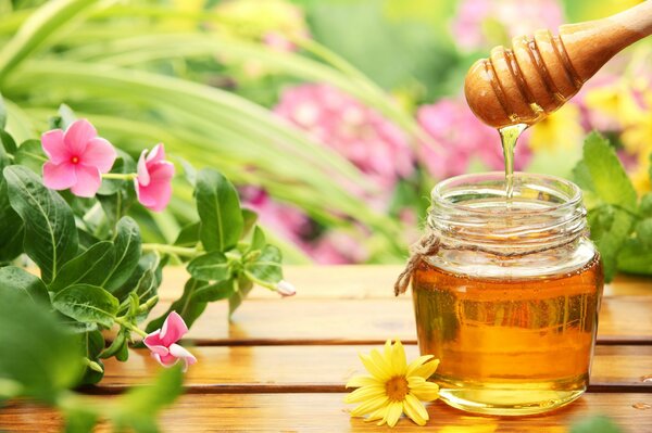 Honey on the table on a background of flowers