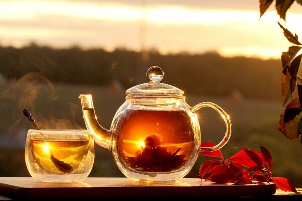 Théière avec thé sur fond de coucher de soleil