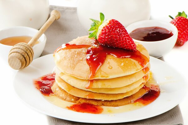 Montagne de crêpes sur une assiette de confiture de fraises et de miel