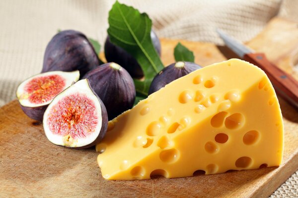 Fruits de figues et un morceau de fromage sur une planche