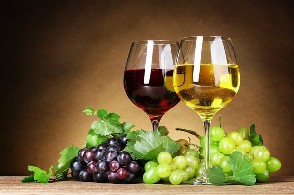 Białe i czerwone wino w kieliszkach z winogronami