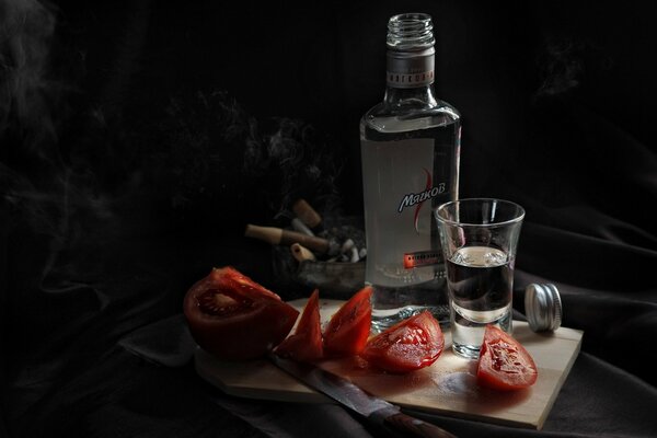 Vodka with tomatoes on a black background