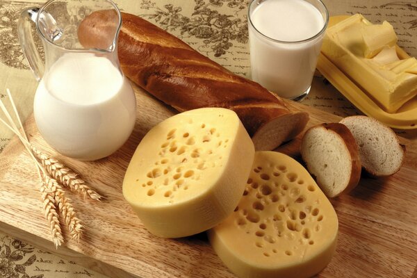 Nature morte comestible faite de lait, de pain, de fromage et de beurre, décorée de céréales sur une planche de bois