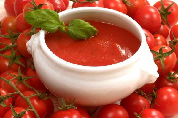 Soupière avec soupe aux tomates et tomates autour